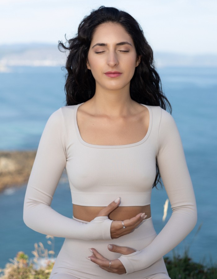 Mujer meditando frente al mar, simbolizando la paz interior y la transformación personal